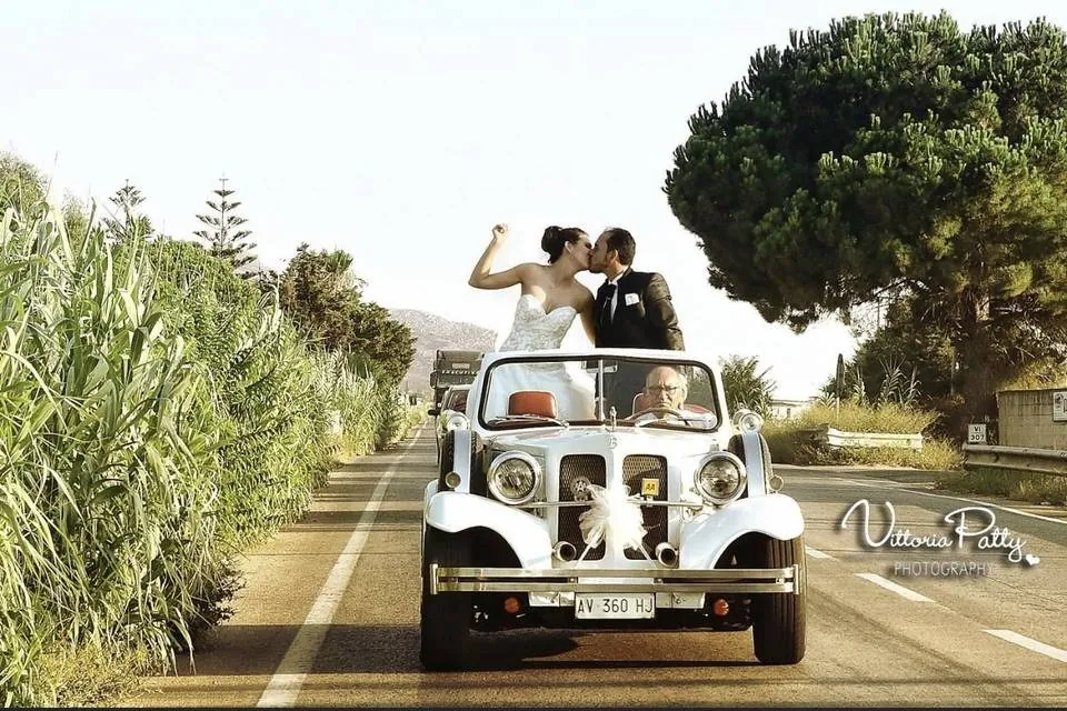 Sposi a bordo di auto d'epoca bianca