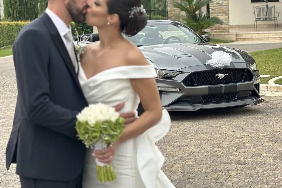 Bacio degli sposi accanto alla Mustang