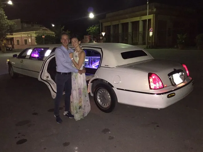 Una coppia accanto alla limousine, di sera